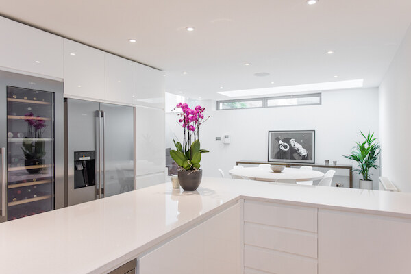 Contemporary white gloss kitchen with wine fridge and dining area