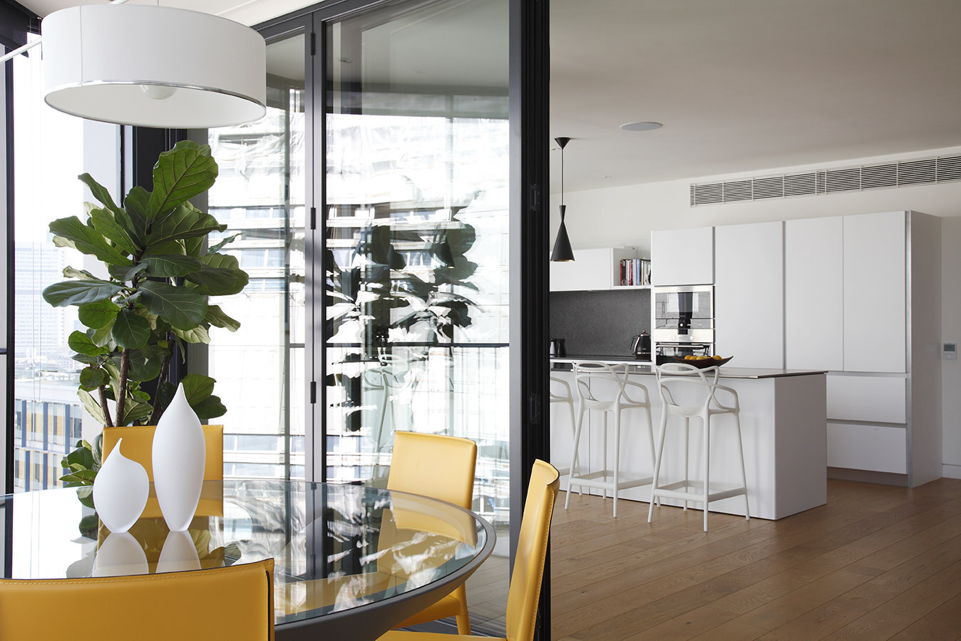 Contemporary dining and kitchen with city view and yellow chairs