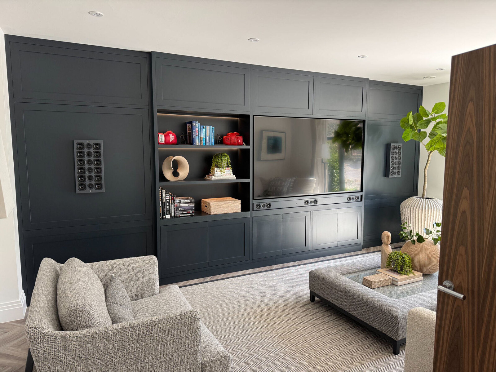 Navy painted media wall with TV, integrated speakers and display shelving