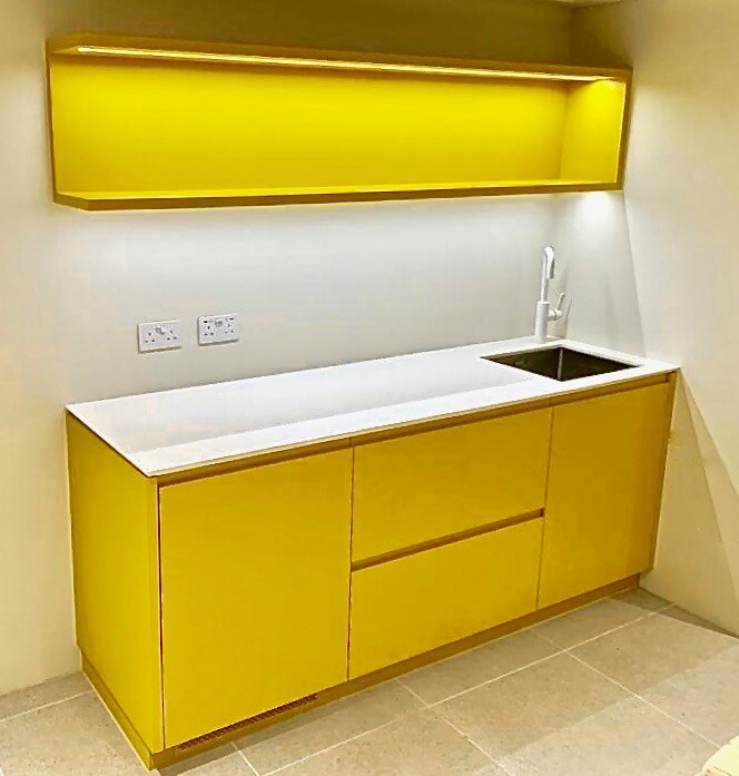 Yellow gloss handleless kitchenette with white worktop