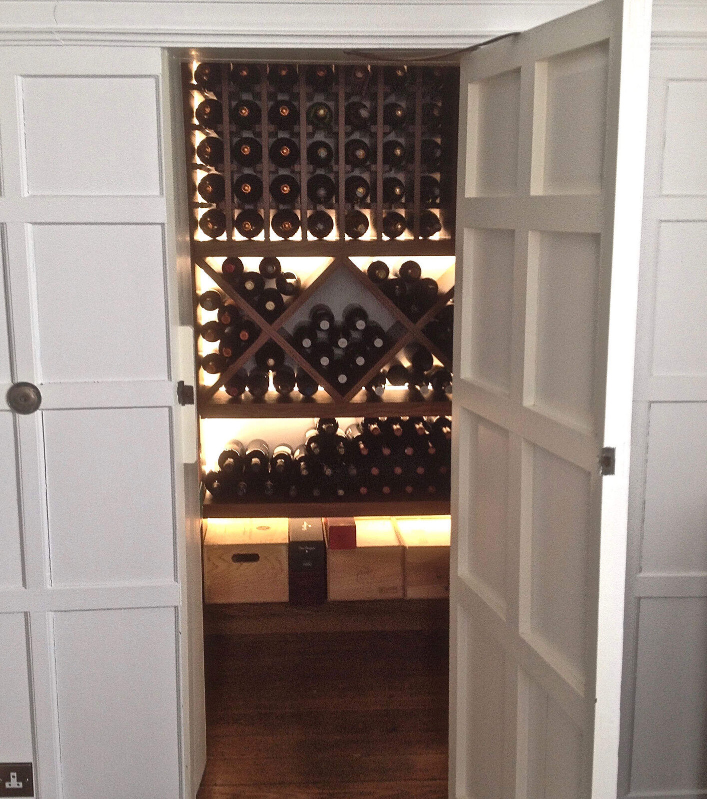 Walk-in wine cellar behind shaker panelled doors with diamond rack