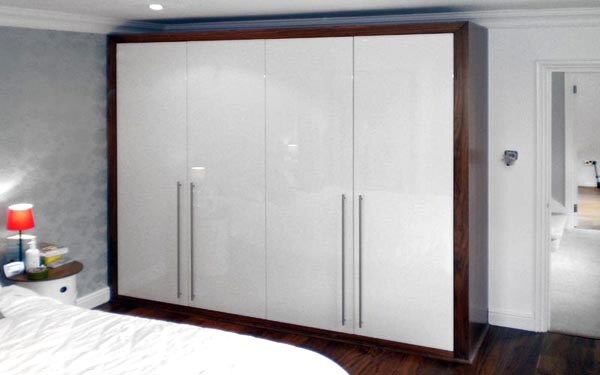 Bespoke white gloss bedroom wardrobe framed in dark walnut