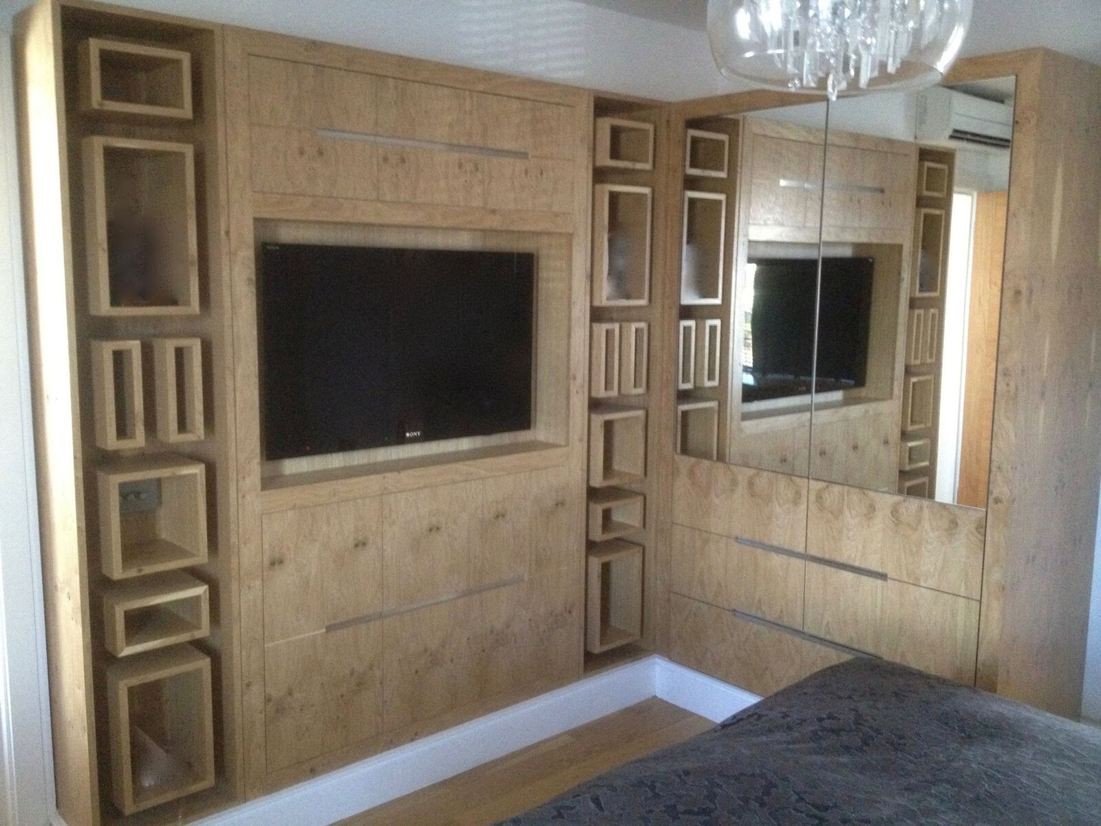 Bespoke oak bedroom wall with integrated TV, mirror and geometric box display shelving