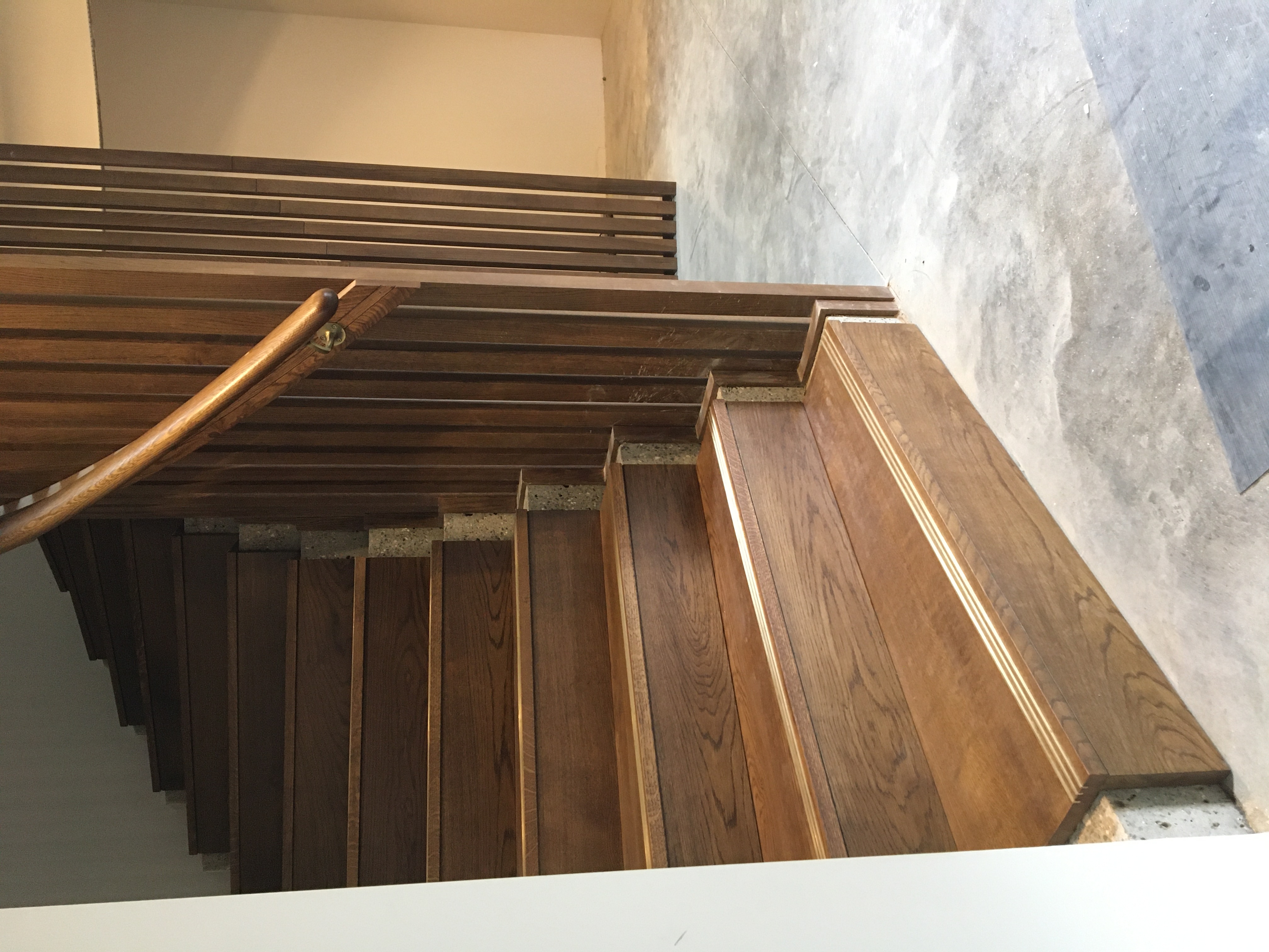 Looking up through a circular walnut slatted staircase drum to a round skylight above