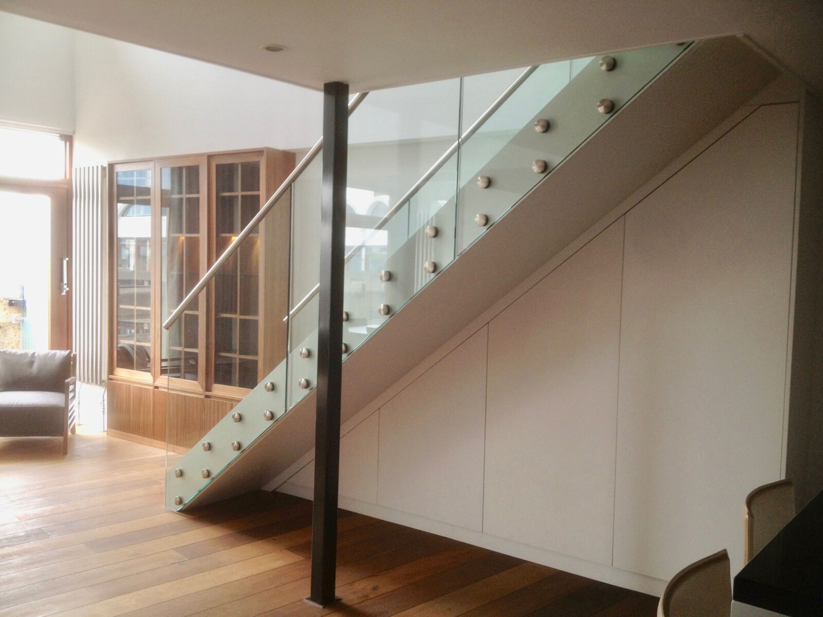 Modern oak study and library with steel-framed glass staircase and under-stair joinery