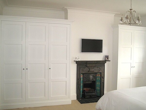 Fitted shaker wardrobes flanking cast-iron fireplace