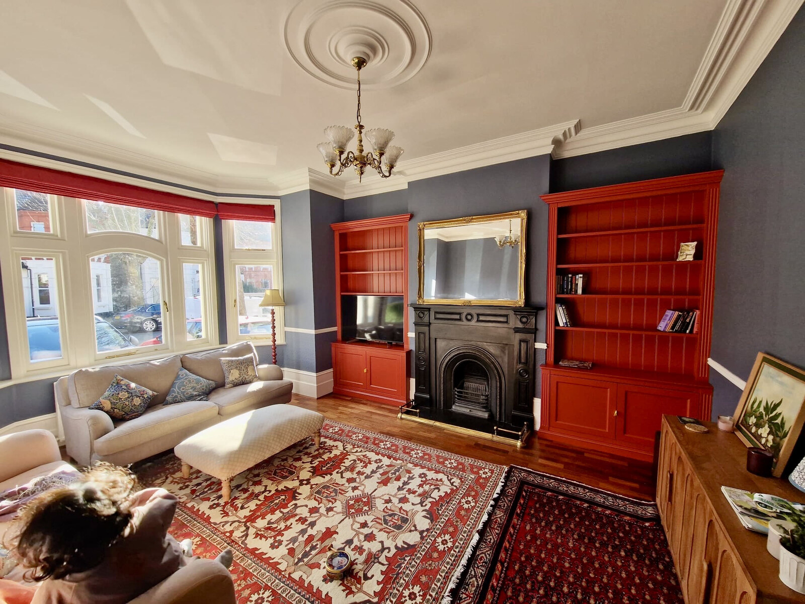 Victorian living room with terracotta painted shaker alcove bookcases flanking cast-iron fireplace