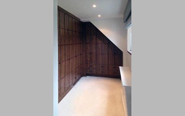 Floor-to-ceiling walnut fitted wardrobes under sloped ceiling